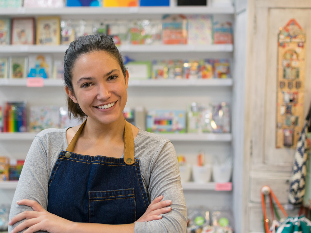 Young woman arms crossed at her store smiling