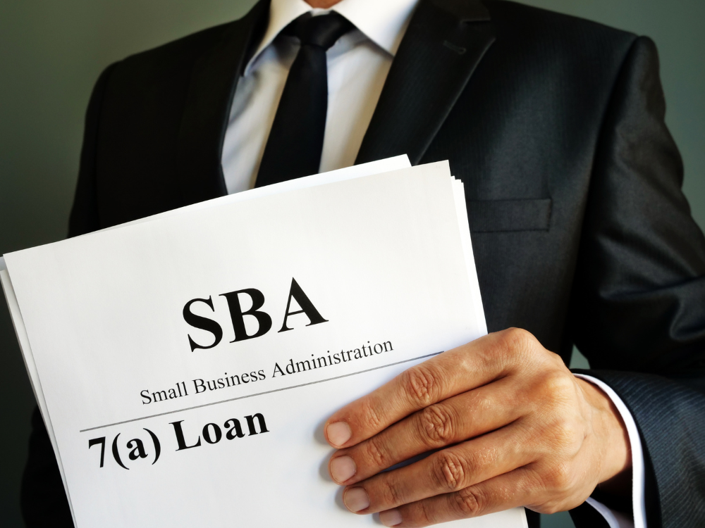 Man holding paper document with SBA 7(a) Loan written on it